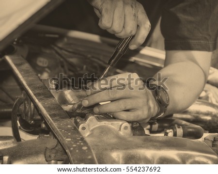 Man at work in a garage. Auto mechanic worker in car repair service. Image of mechanic hands with a tool. Auto repair concept. Close up. Black White vintage. Nice background for your text. Matte 