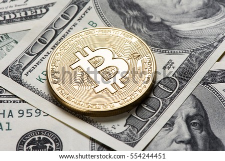 golden bitcoin coin on us dollars close up Royalty-Free Stock Photo #554244451