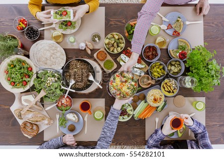 Friends having vegetarian feast, sitting at rustic table