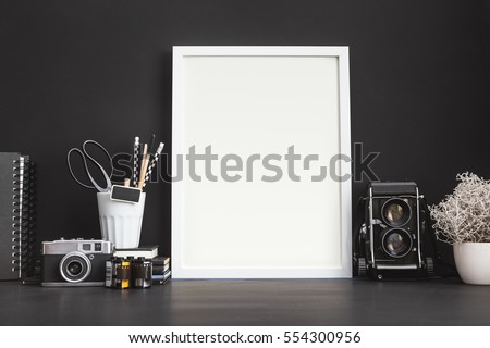Mock up photo frame on a black wall with medium format camera.