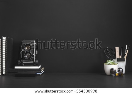Photographer or hipster workspace. Black background with medium format camera, notebooks, etc. 
