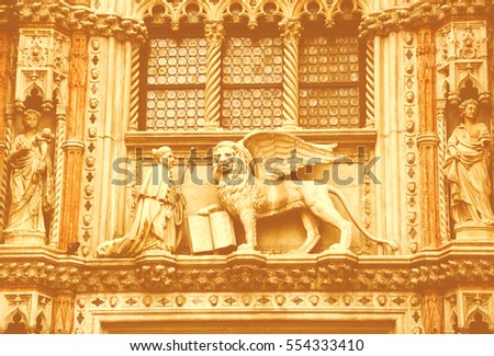 Doge and winged lion holding book on the Gothic style portal over the entry to Doge's Palace in Venice (Italy). Soft light toned photo.