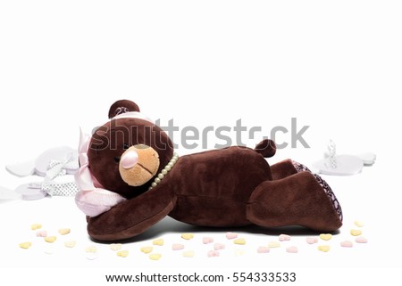 Plush toy bear lying on its side with a pink heart on isolated white background. Valentine day