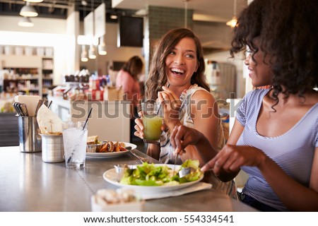 Two Women Enjoying Lunch Date In Delicatessen Restaurant Royalty-Free Stock Photo #554334541