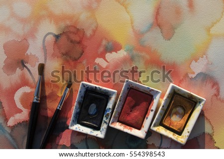 Color pans with brushes on poppies watercolor background