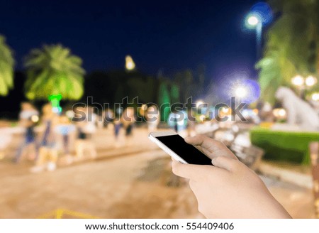 woman use mobile phone and blurred image of people in the park at night