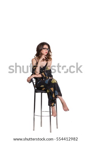 Isolated close-up portrait of young elegant girl sitting on a chair, hair curls, the glasses look at camera
