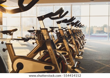 Modern gym interior with equipment. Fitness club with row of training exercise bikes. Healthy lifestyle concept