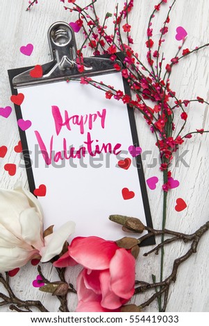 Valentine background with coloured hearts and flowers on white wooden background