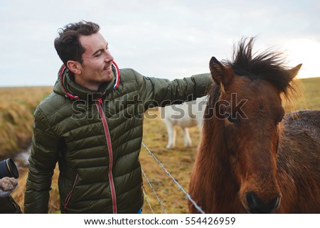 man petting red horse at sunset