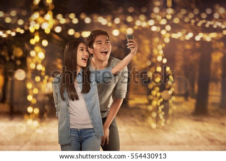 Happy asian couple in love taking selfie photo with smartphone