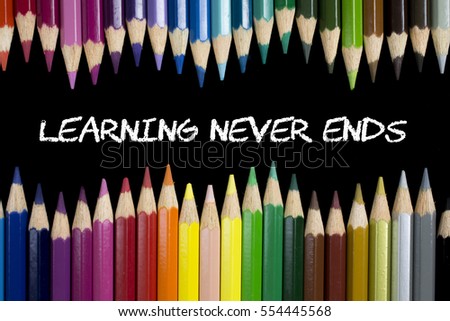 Education Concept : Learning Never Ends on blackboard with colorful pencils as a frame.
