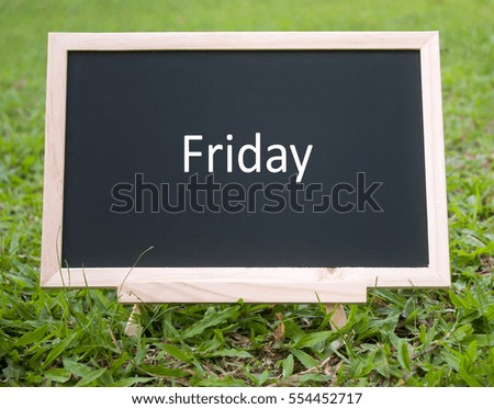 mini blackboard with word friday isolated over grass field background