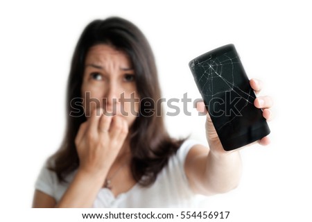 Young woman  emotionally reacts on broken phone. Pretty woman holding crashed mobile phone in her hand. Selective focus on broken display of cracked smartphone. Isolated on white background