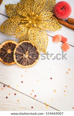 vertical shot 
cinnamon sticks, cloves Dried orange ornamental red apple, gold poinsettia on a blue background with vertical boards