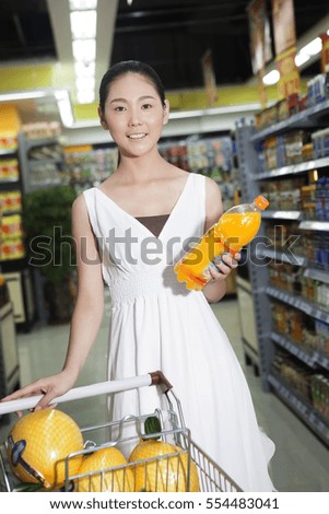 	A young woman in the supermarket to buy drinks	