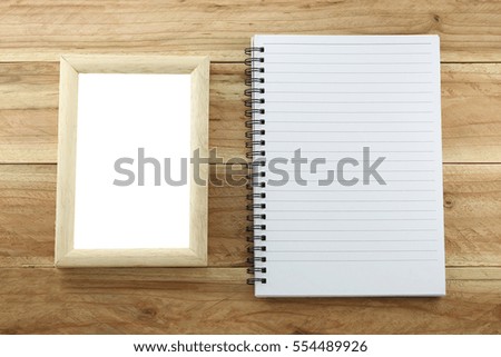 Wooden frame and empty notebook on brown wood background.