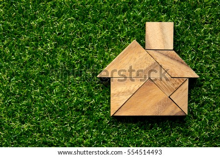 Tangram puzzle in home shape on artificial green grass background (Concept for dream home)