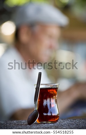 Turkish tea served in traditional glass and old man in background
