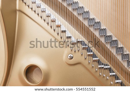 Golden metal frame of grand piano with silver parallel strings