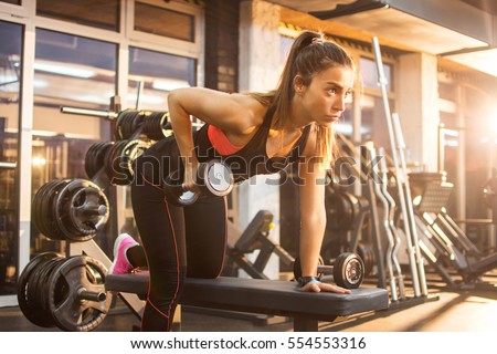 Sportswoman lifting weights in gym. Royalty-Free Stock Photo #554553316