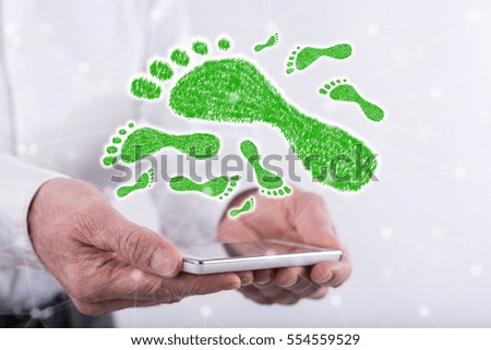 Carbon footprint concept above a smartphone held by hands
