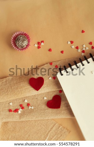 Valentines Day background with chocolate balls, red hearts and notebook