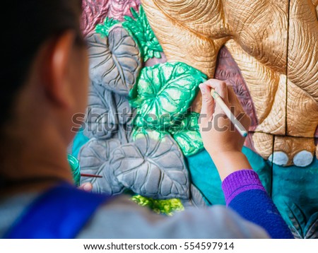 Hand of artist painting asia elephant and tree