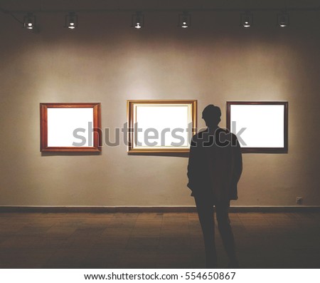 Man in gallery room looking at empty picture frames - Mock up art concept