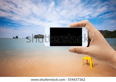 Man use mobile phone, blur image of the beach as background.