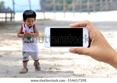 Man use mobile phone, blur image of the beach as background.