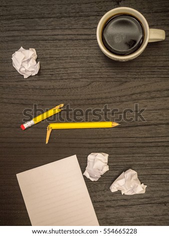 Dark surface, paper wads, broken pencil, coffee, frustration