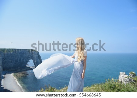 Girl with blond hair in dress on the edge of the cliff into the sea in the north of France