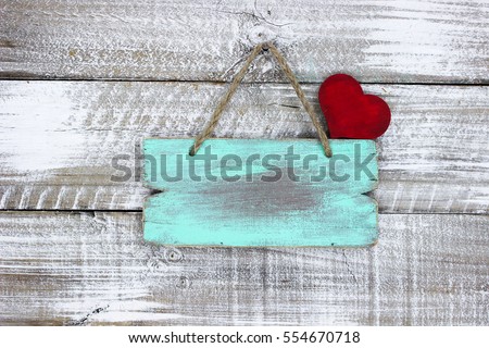 Blank turquoise wood sign with red heart hanging from rope on rustic antique white painted wooden background; Valentine's Day, Mother's Day and love concept with copy space
