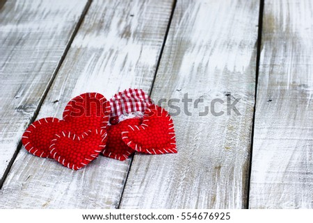 Pile of red country fabric hearts on white painted rustic antique wooden background; Valentine's Day and love concept with white copy space for text