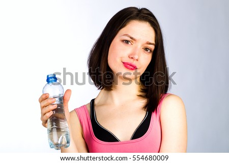 Young girl with a bottle of drinking water on a white background, studio lighting