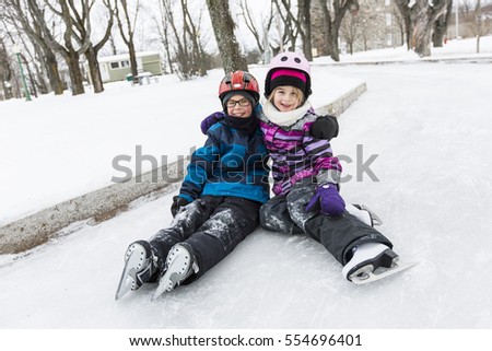 A little girl and brother enjoying ice skating in winter season