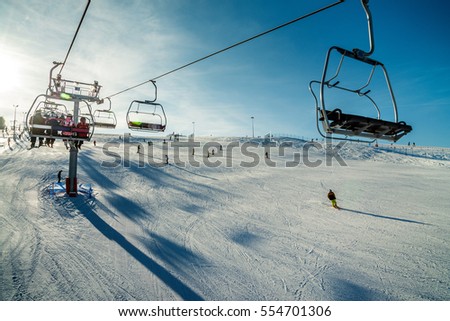 Skiers on the chairlift - ski resort Tylicz during winter sunny day