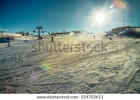 Skiing on slope - winter sunny day in Tylicz village  Royalty-Free Stock Photo #554703613