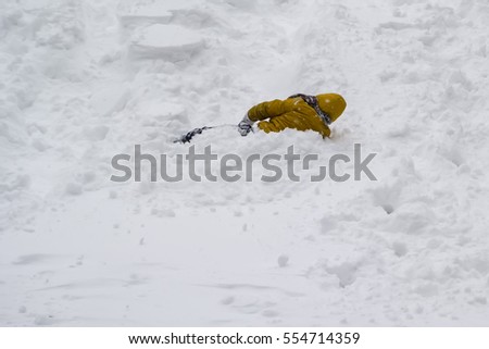 child playing with snow, has got yellow wear, weather is winter