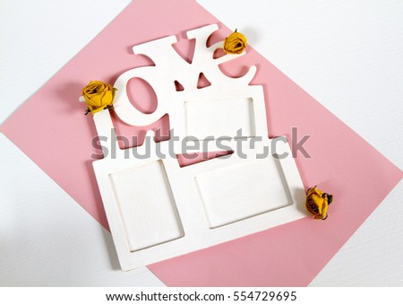 Frame for photo with letter wooden fishing on a pink and white background. Dried buds with yellow roses