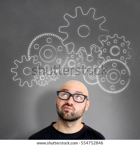 View of Gear wheel going out of the head of a young attractive thinking man geek with glasses
