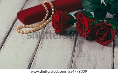 Roses and gift box with bead on wooden table. Valentines day concept. Copy space. Instagram toned image.