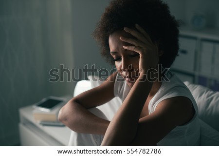 Sad depressed woman suffering from insomnia, she is sitting in bed and touching her forehead, sleep disorder and stress concept Royalty-Free Stock Photo #554782786
