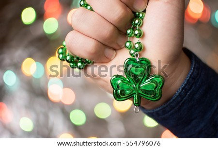 Male hand holding green clover necklace. St Patricks day preparation