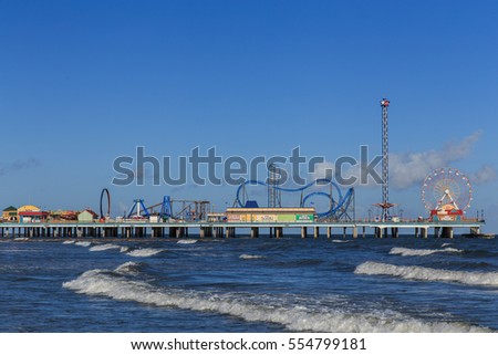 Pleasure Pier from the water/ Galveston Island Pleasure Pier/ The Pleasure Pier rides reaching out over the water on Galveston, Texas, USA. Royalty-Free Stock Photo #554799181