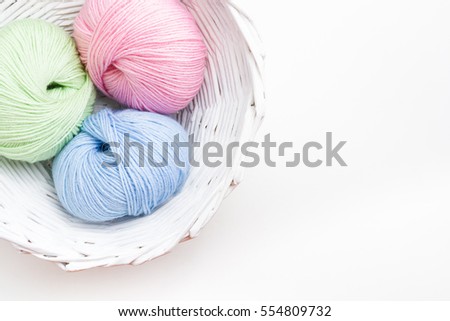 Pastel colored yarn in white basket. Copy space.