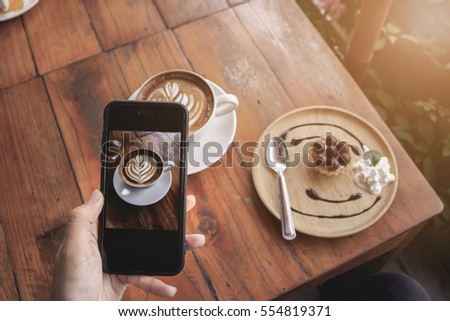 Young girl using Photography of smartphone of latte art coffee on mobile camera display while shooting.