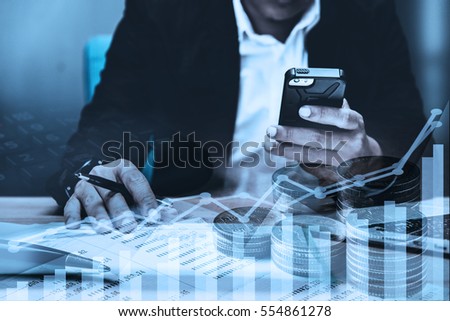 double exposure of businessman working with laptop,smartphone,laptop and row of coins with diagram and digital interface in finance and business concept