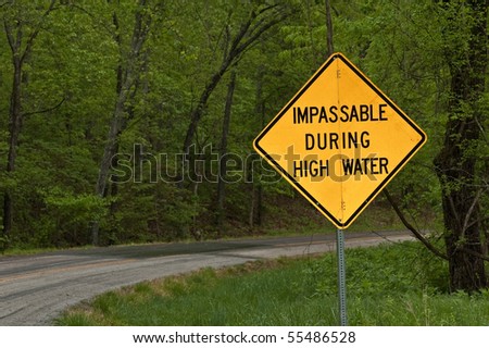 a sign on a secondary road in the foothills of the Ozark Mountains in southeast Missouri warning of an impassable road in event of high water